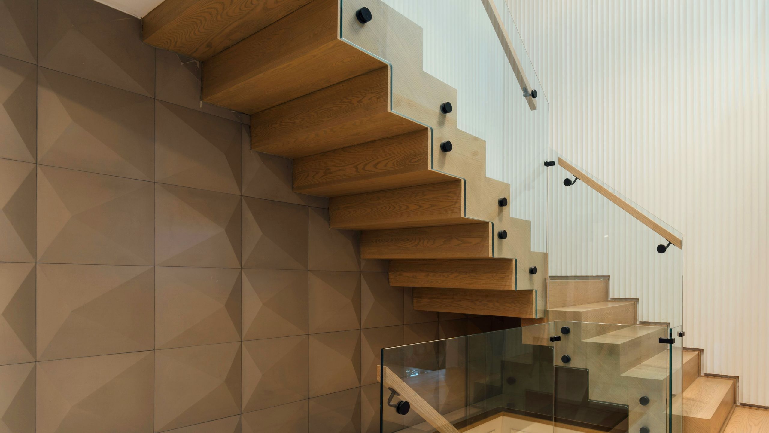Escalier suspendu à marches de chêne massif et garde-corps de verre, dans un intérieur résidentiel contemporain