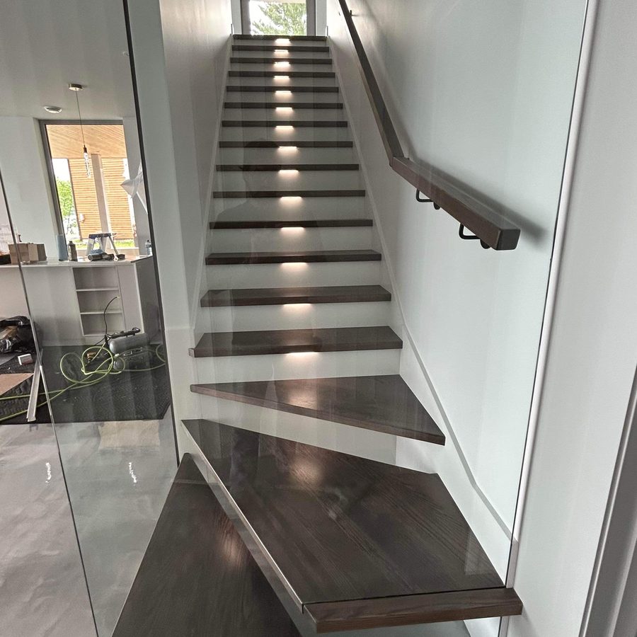 Escalier à marches foncées avec garde-corps de verre et main courante d'acier noir